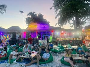 a group of people sitting in lawn chairs in front of a house at Moon house Beach Hostel in Haad Rin