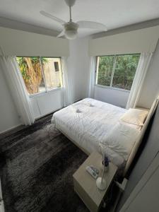 a white bedroom with a bed and two windows at Georges 2 Bedroom Apartment in Limassol