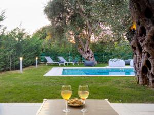 two glasses of wine on a table next to a pool at Galene Eco Luxury Villas in Acharavi