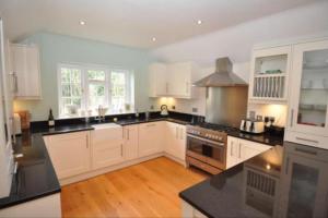 a large kitchen with white cabinets and black counter tops at New Forest Cottage in Lyndhurst