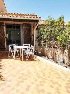 a patio with a table and chairs on a house at Micro-maison 100m de la plage in Le Barcarès