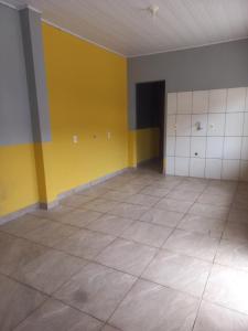 an empty room with yellow and white walls and tile floors at Kitnet de temporada in Porto Belo