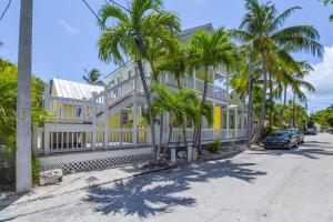 a yellow house with palm trees in front of a street at VanGogh Studio in Key West