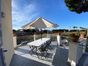 een witte tafel met een parasol op een balkon bij La casa di Carlotta in Loano