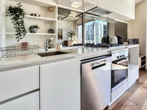 a kitchen with white cabinets and stainless steel appliances at Beautiful 1B1B Prahran apartment in Melbourne