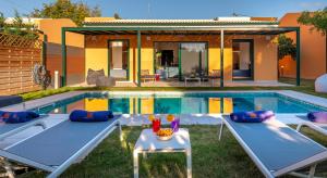 a swimming pool with two beds in front of a house at Galene Eco Luxury Villas in Acharavi +105 photos