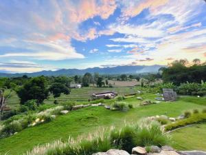 a field of grass with a house in the distance at Monko Mini room in Pai