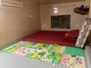 ein kleines Zimmer mit einem Bett mit einer roten Matratze in der Unterkunft House ĐDT in Hanoi