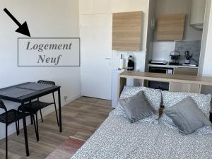 a living room with a couch and a table and a kitchen at Studio Horizon Bleu, vue mer in Calais