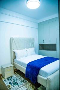 a bedroom with a white bed with a blue blanket at Luxury modern Apartment in Nairobi +17 photos