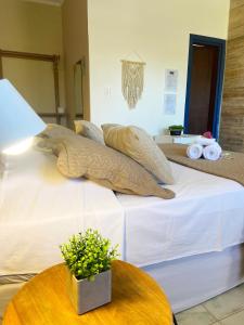 a bed with pillows on top of it with a table at Pousada Luz do Sol in Carrancas