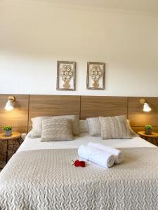 a bedroom with a large white bed with towels on it at Pousada Luz do Sol in Carrancas