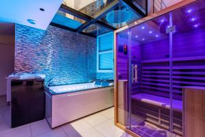 a bathroom with a tub and a shower with purple lighting at GlamappartSpa Prestige New-York expérience in Reims