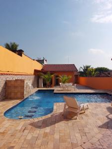 een zwembad met een stoel naast een huis bij Casabelamare Itanhaém in Itanhaém