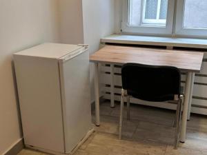 波兹南Gołębia 4 Rooms的厨房配有桌子、冰箱和椅子