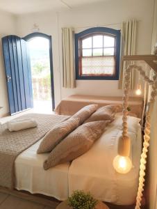 a bedroom with a bed with pillows and a window at Pousada Luz do Sol in Carrancas