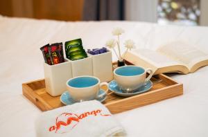a tray with two cups and a book on a bed at Amango Home in Ho Chi Minh City