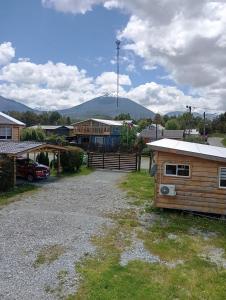 a small wooden house with a mountain in the background at Cabañas a orillas de rio in Hornopiren +11 photos