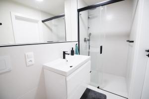 a white bathroom with a sink and a shower at Apartmán Dominanta in Liptovský Mikuláš +4 photos