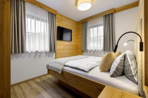 a bedroom with a bed with a television and windows at Bauernhof Auhof in Wagrain