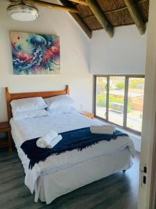 una camera da letto con un letto grande con un dipinto sul muro di At Sea, Melkbosstrand a Melkbosstrand