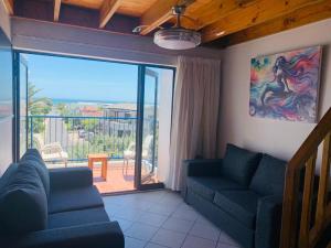 a living room with two blue couches and a balcony at At Sea, Melkbosstrand in Melkbosstrand