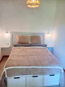 a bedroom with a large bed with a brown blanket at Prunus Casa de Montaña in El Hoyo