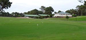 a green golf course with a building in the background at CHALET B NATURISTe MAEVA in Le Porge