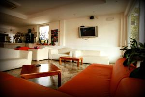 a living room with white couches and a tv at Hotel Marebello in Rimini