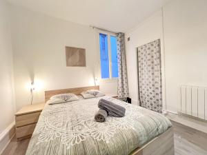 - une chambre blanche avec un grand lit et une valise dans l'établissement LE MONTAIGNE - Wifi fibre- Coeur du centre ville-PROPERTY RENTAL NM, à Périgueux