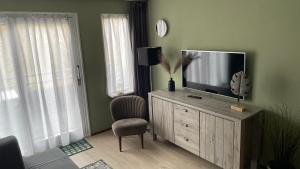 a living room with a television on a wooden dresser at Appartement De Parel, Resort Amelander Kaap in Hollum