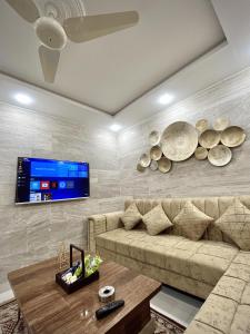 a living room with a couch and a tv on a wall at Kings Den 1BHK in Rawalpindi