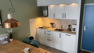 eine Küche mit weißen Schränken und einem Holztisch in der Unterkunft Appartement De Bosrand, Resort Amelander Kaap in Hollum