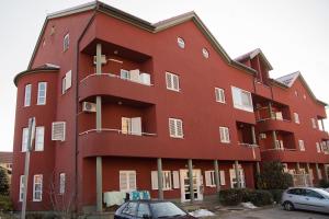 een rood gebouw met auto's ervoor geparkeerd bij Apartment Giro in Zagreb