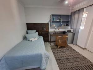 a bedroom with a blue bed and a desk at Emmaus Single Room in Bloemfontein