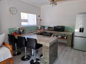 a kitchen with a counter with chairs and a refrigerator at Emmaus Apartment in Bloemfontein