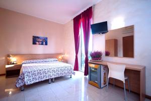 a bedroom with a bed and a desk with a television at Hotel Villa Flora in Bogliasco