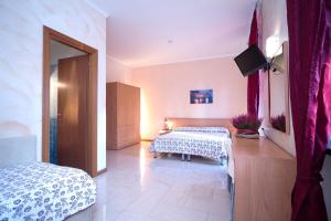 a bedroom with two beds and a television in it at Hotel Villa Flora in Bogliasco