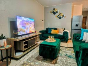a living room with green couches and a flat screen tv at MateezSpace in Boksburg