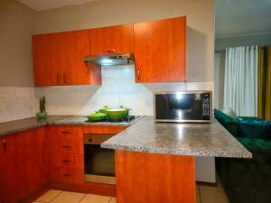 a kitchen with wooden cabinets and a microwave at MateezSpace in Boksburg