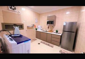 a small kitchen with a refrigerator and a stove at شقة العقيق الأولى in Medina +20 photos