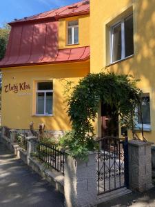 a yellow house with a fence and a door at Zlatý Klas in Mariánské Lázně