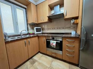 a kitchen with wooden cabinets and a stainless steel refrigerator at Casa de Lino in Laxe