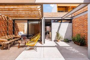 a patio with a yellow chair and a couch at Casa Franco - Modern Architecture Home with AC in San Miguel de Allende