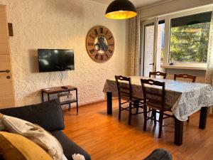 a living room with a table and a clock on the wall at Central recently renovated apartment - Casa Tre Pini in Madonna di Campiglio