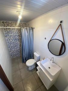 een badkamer met een wastafel, een toilet en een spiegel bij Casa com piscina capão da canoa in Capão da Canoa +5 foto's
