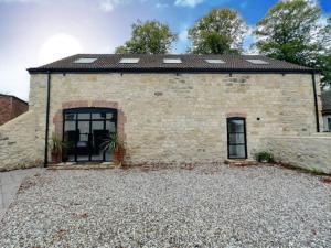 Casa de ladrillo con ventanas y entrada de grava en Church Barn House, Wadworth, en Wadworth