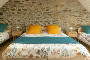 a bedroom with a bed with yellow pillows and a stone wall at La boulangerie appartement 2 in Janzé