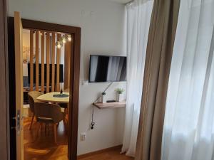 Habitación con mesa, TV y puerta. en Brzece lux apartman, en Brzeće 7 fotos más