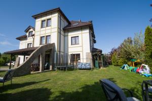 a large white house with chairs in the yard at Willa Hydrograf in Ustka